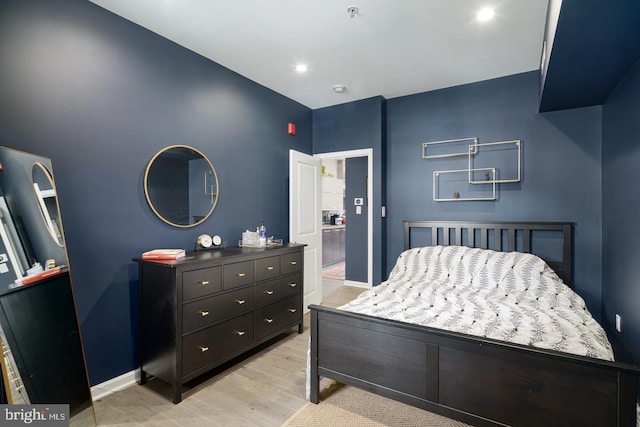 bedroom with ensuite bath and light hardwood / wood-style flooring