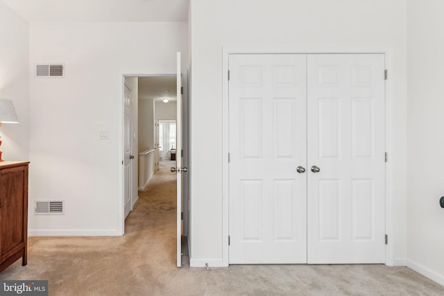 unfurnished bedroom with light colored carpet and a closet