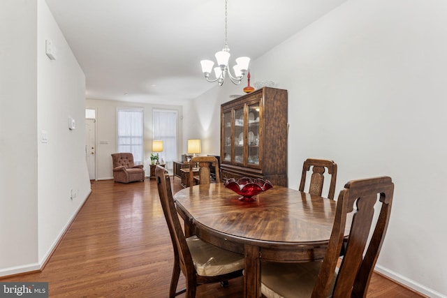 dining space with wood-type flooring and a notable chandelier