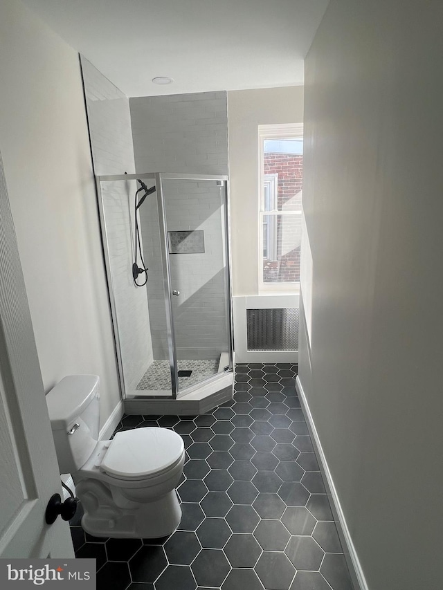 bathroom featuring tile patterned flooring, toilet, and an enclosed shower