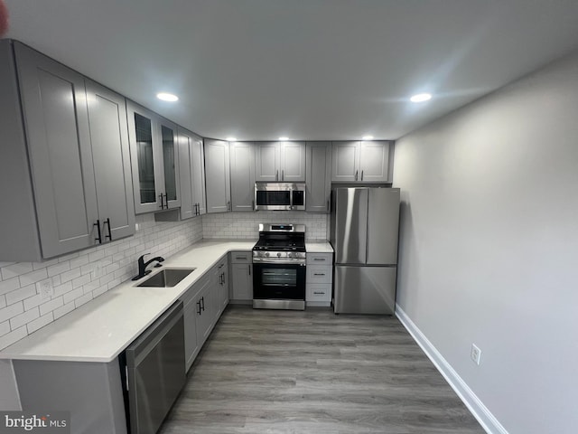 kitchen featuring gray cabinetry, light wood-type flooring, appliances with stainless steel finishes, and sink