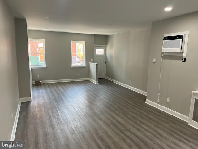 unfurnished room featuring a wall unit AC and dark hardwood / wood-style flooring