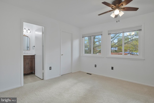 unfurnished bedroom featuring ceiling fan, light colored carpet, and connected bathroom