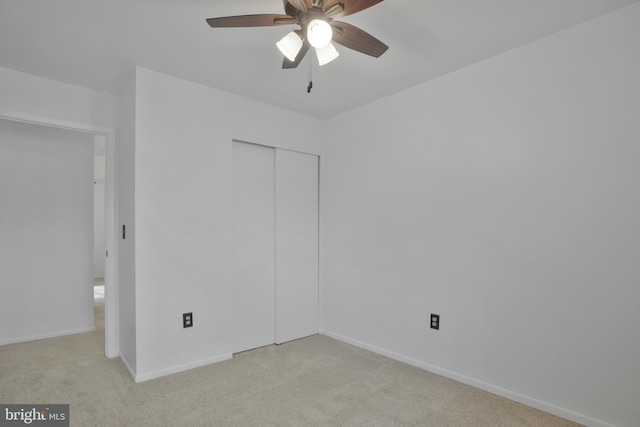 unfurnished bedroom with light carpet, a closet, and ceiling fan