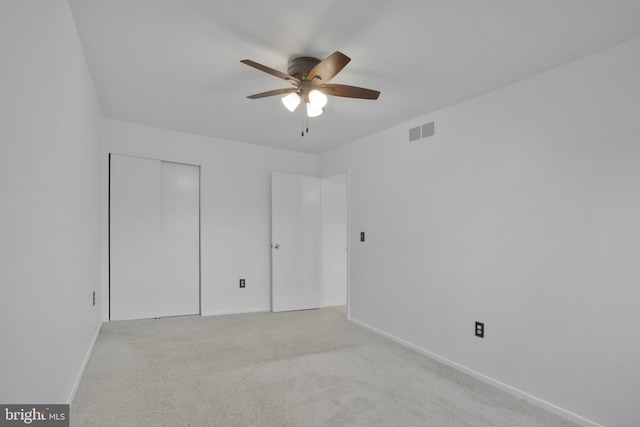 unfurnished bedroom featuring ceiling fan, light colored carpet, and a closet