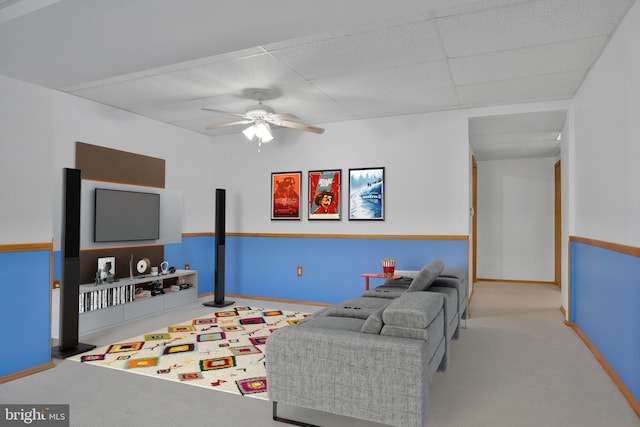 living room with a drop ceiling, ceiling fan, and light carpet