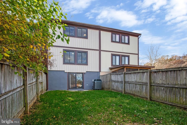 rear view of property featuring a lawn and central air condition unit