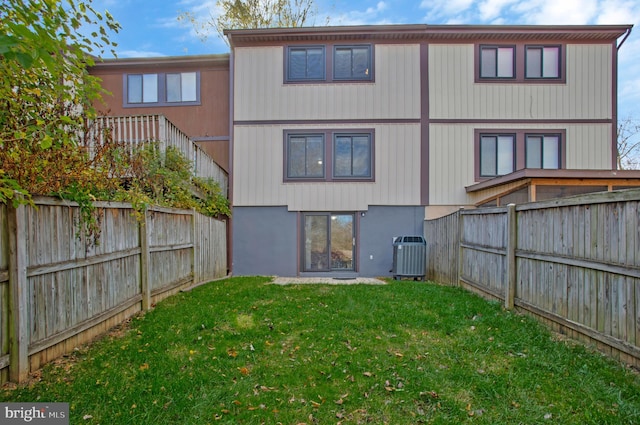 back of house with a yard and central AC