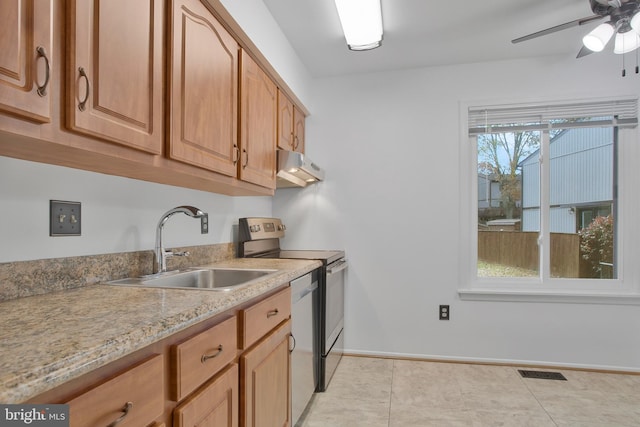 kitchen with sink, ceiling fan, light tile patterned floors, appliances with stainless steel finishes, and light stone counters