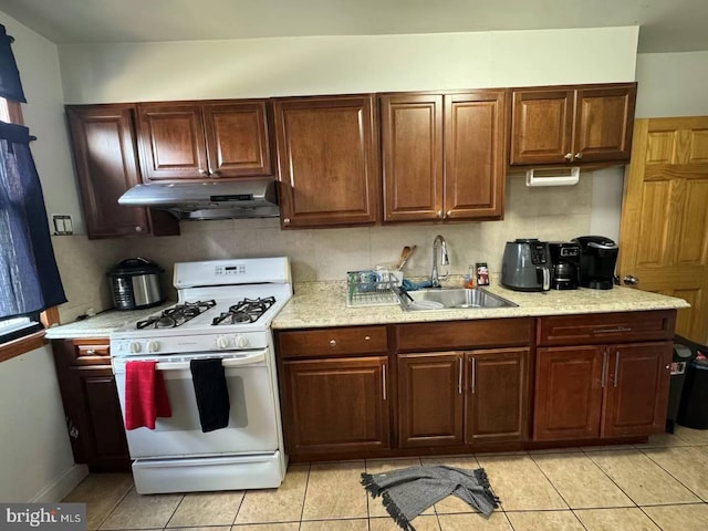 kitchen with light tile patterned floors, white gas range, and sink