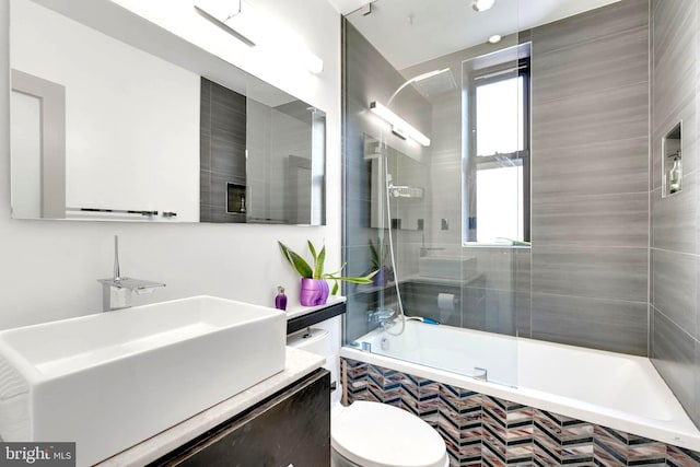 full bathroom featuring vanity, tiled shower / bath combo, and toilet