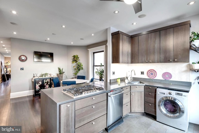 kitchen featuring sink, appliances with stainless steel finishes, dark brown cabinets, kitchen peninsula, and washer / clothes dryer