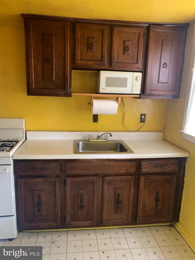 2413 Iverson St, Temple Hills, MD 20748 - kitchen featuring white appliances, a sink, light countertops, and dark brown cabinetry