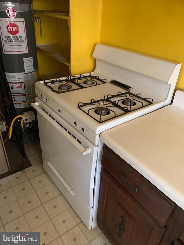 2413 Iverson St, Temple Hills, MD 20748 - kitchen featuring white range with gas stovetop, water heater, light countertops, and dark brown cabinetry