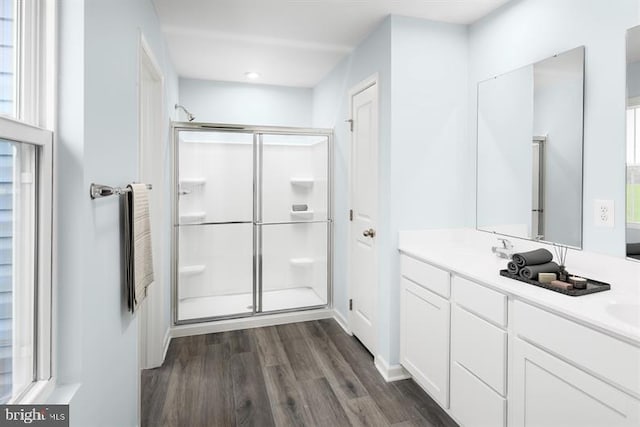 bathroom with hardwood / wood-style flooring, a shower with shower door, and vanity