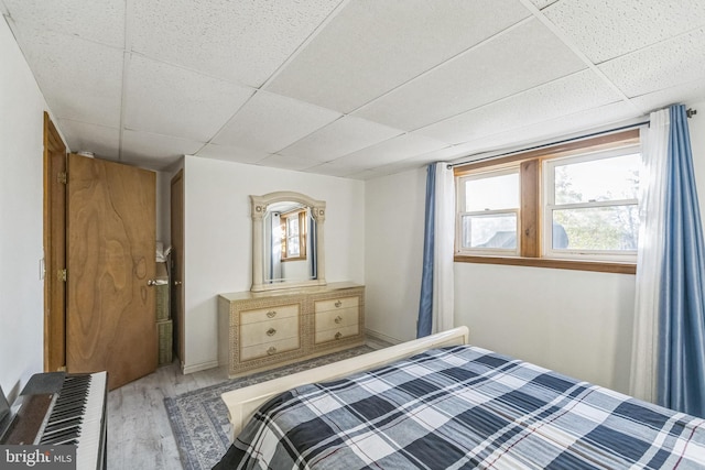 bedroom with a paneled ceiling and wood-type flooring