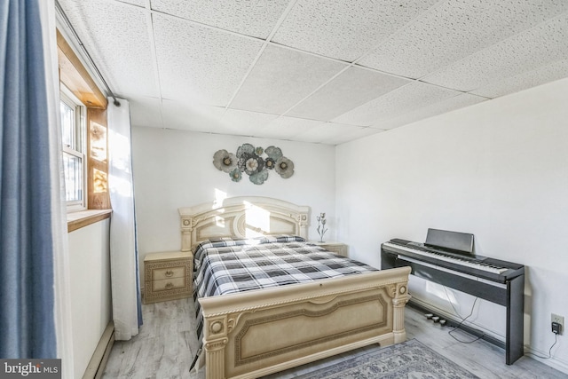 bedroom with a paneled ceiling and light wood-type flooring