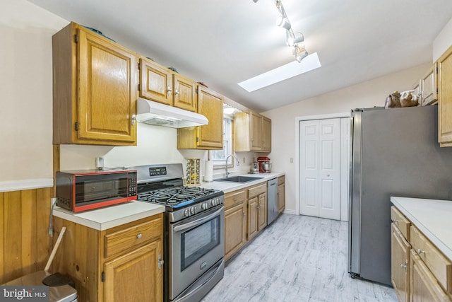 kitchen with vaulted ceiling with skylight, sink, light hardwood / wood-style floors, and appliances with stainless steel finishes