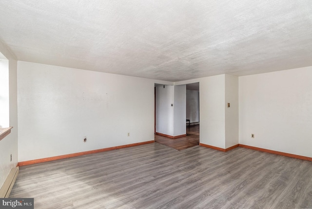 spare room with baseboard heating, a textured ceiling, and hardwood / wood-style flooring