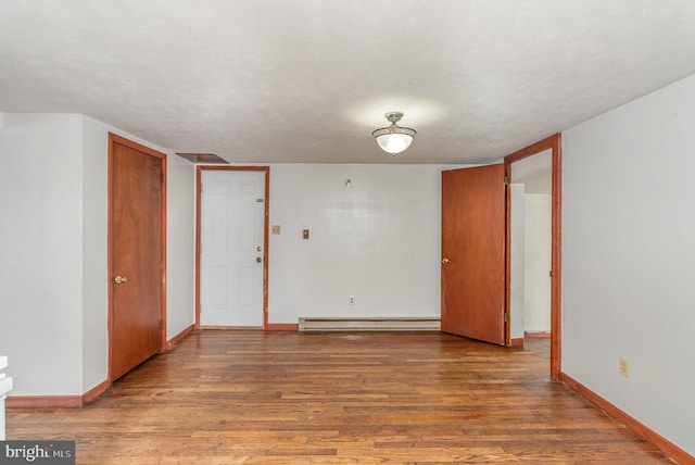 empty room with a baseboard radiator, wood-type flooring, and a textured ceiling