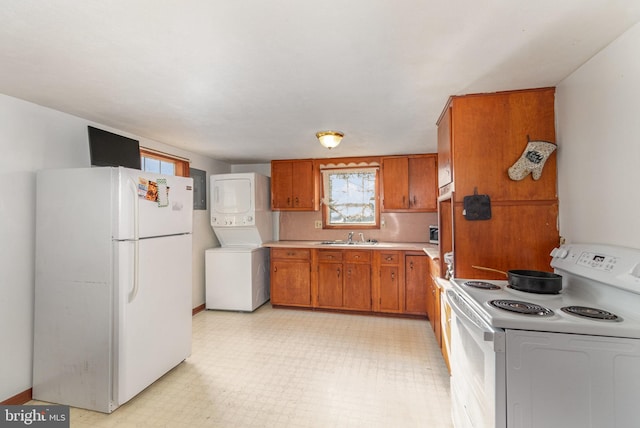 kitchen with white appliances, stacked washer and dryer, sink, and backsplash