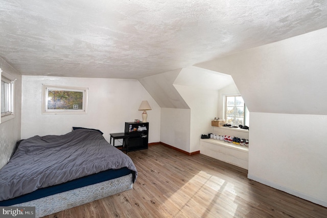 bedroom featuring a textured ceiling, hardwood / wood-style flooring, and vaulted ceiling