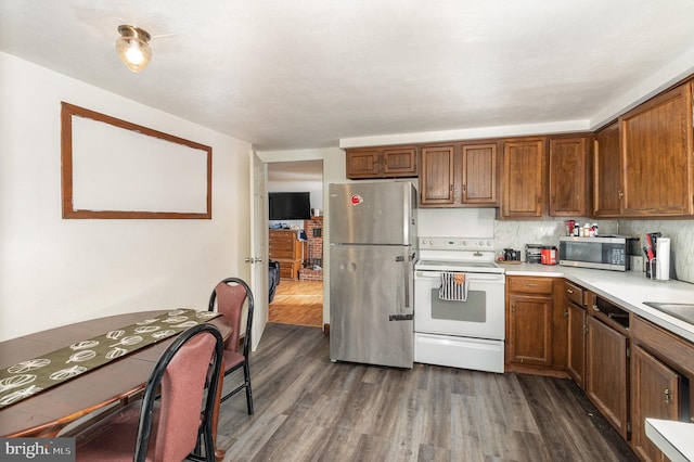 kitchen with dark hardwood / wood-style flooring, backsplash, and appliances with stainless steel finishes