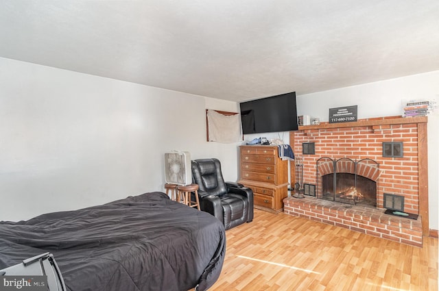 bedroom featuring a brick fireplace and hardwood / wood-style floors