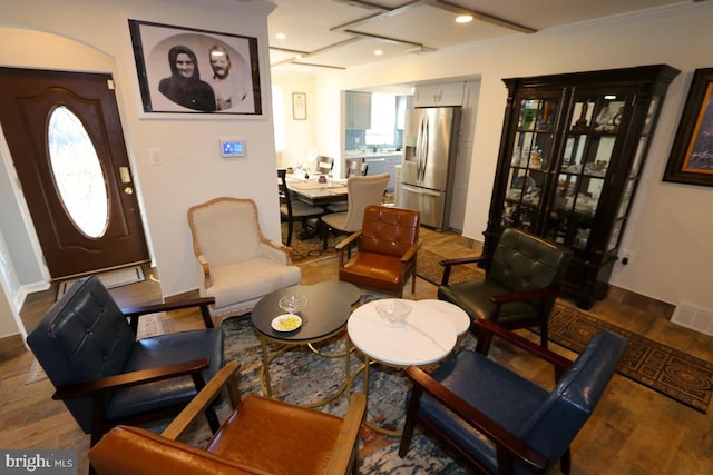 living area with plenty of natural light, hardwood / wood-style flooring, and crown molding