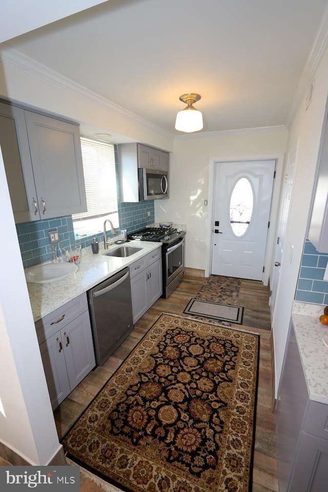 kitchen with sink, appliances with stainless steel finishes, tasteful backsplash, crown molding, and gray cabinetry