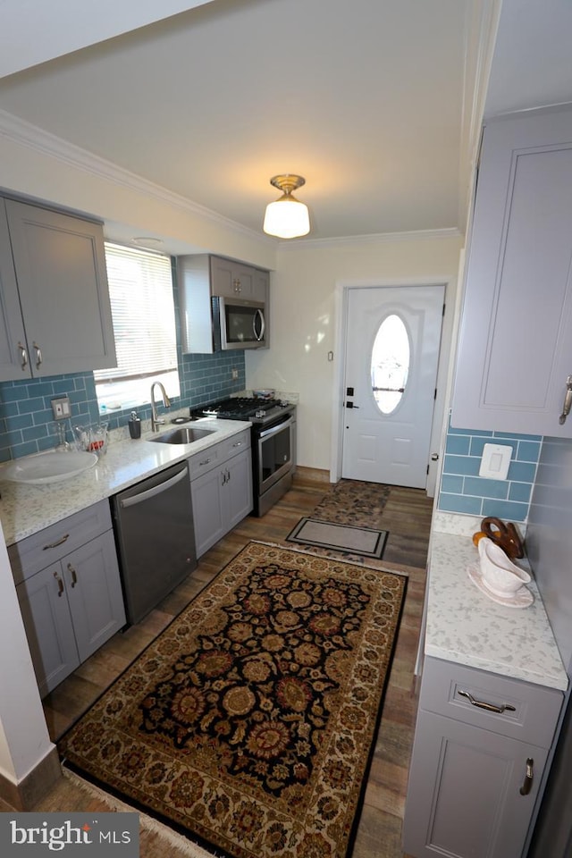 kitchen featuring sink, appliances with stainless steel finishes, ornamental molding, backsplash, and gray cabinetry