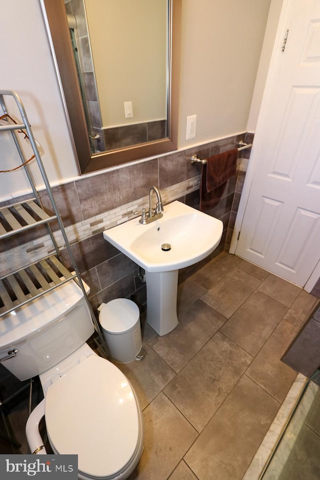 bathroom featuring toilet and tile walls