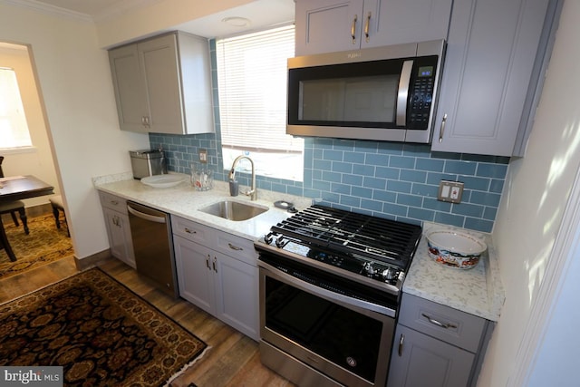 kitchen featuring stainless steel appliances, sink, ornamental molding, dark hardwood / wood-style floors, and gray cabinetry