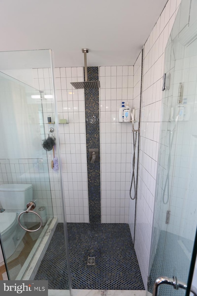 bathroom featuring walk in shower, toilet, and tile walls