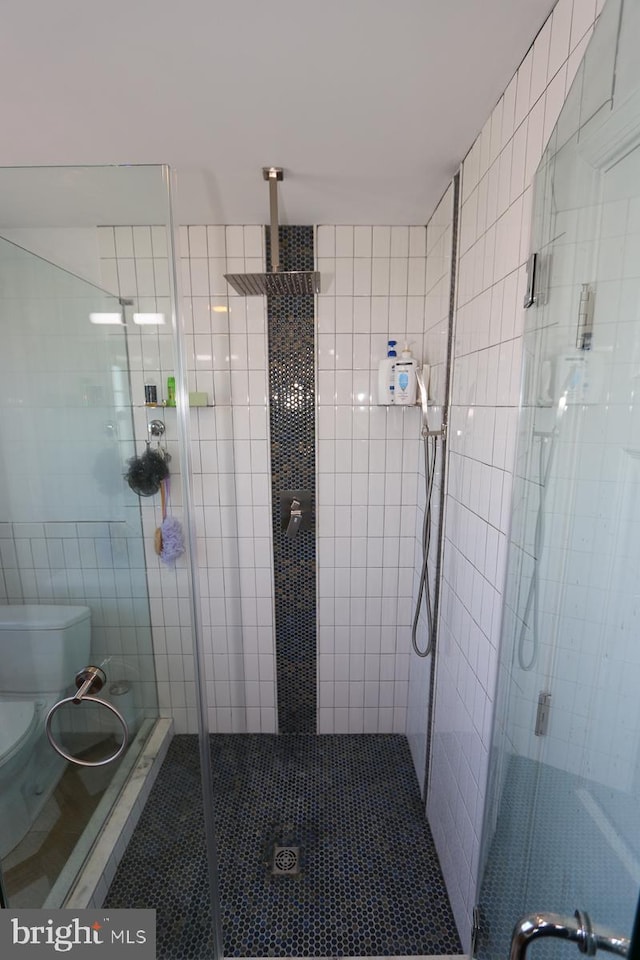 bathroom featuring a shower with shower door and toilet