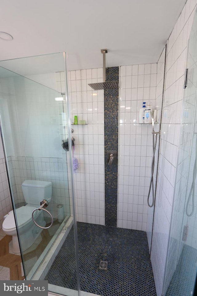 bathroom with walk in shower, toilet, and tile walls