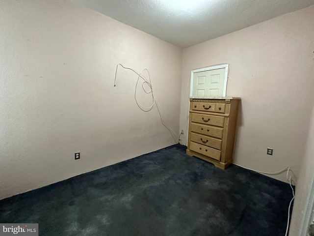 unfurnished room featuring dark colored carpet and a textured ceiling