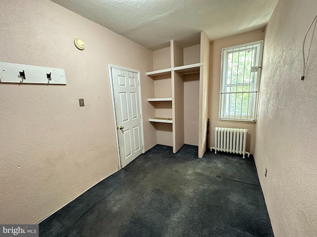 interior space with dark colored carpet, a textured ceiling, and radiator