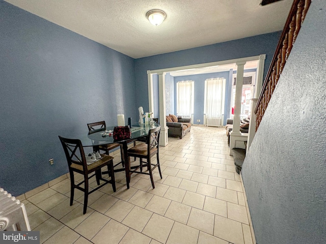 dining space featuring a textured ceiling and ornate columns