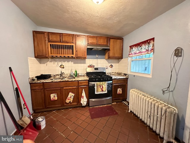 kitchen with stainless steel range with gas stovetop, sink, tasteful backsplash, radiator, and a textured ceiling