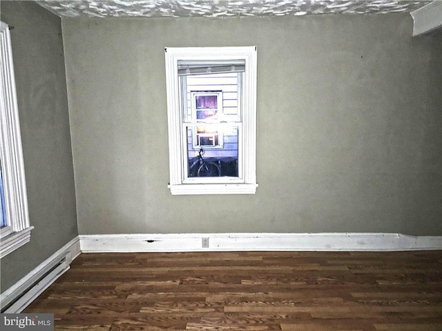 empty room featuring a baseboard radiator and dark hardwood / wood-style flooring