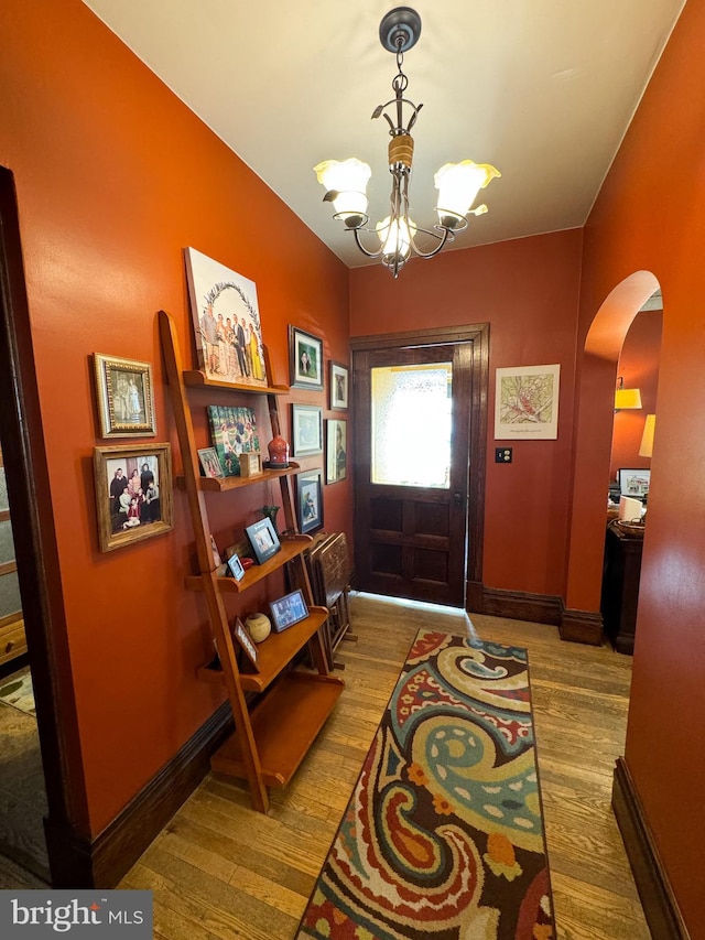 entryway featuring wood-type flooring and an inviting chandelier