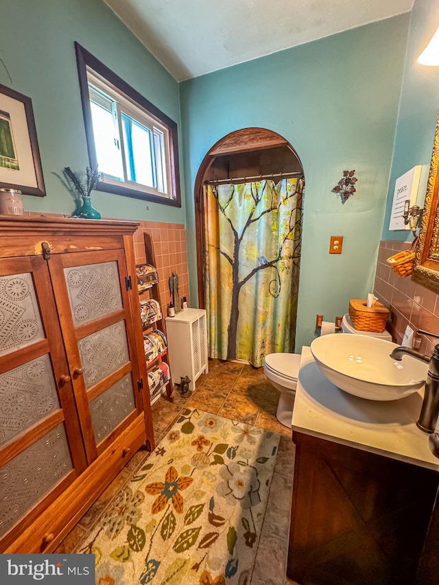 bathroom featuring tile patterned flooring, vanity, toilet, and tile walls