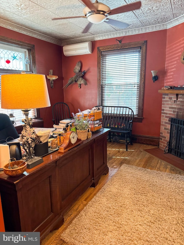 office featuring a wall unit AC, ceiling fan, light hardwood / wood-style flooring, and a healthy amount of sunlight