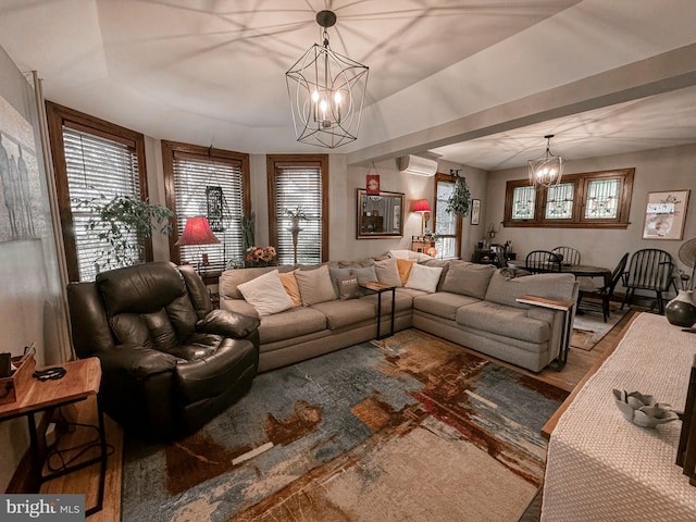 living room with a wall mounted air conditioner, wood-type flooring, and an inviting chandelier