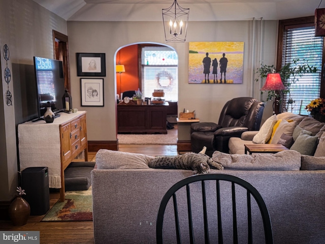 living room with a healthy amount of sunlight, wood-type flooring, and a notable chandelier