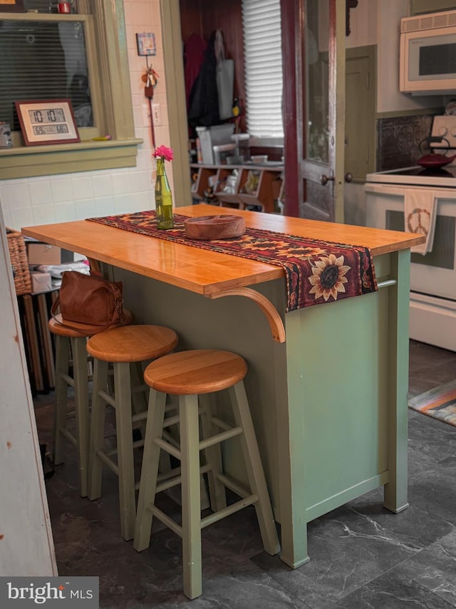 kitchen featuring butcher block countertops, white appliances, and a breakfast bar area