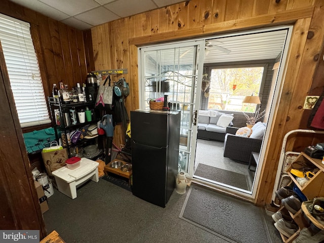 entryway featuring a paneled ceiling, carpet flooring, wood walls, and a wealth of natural light