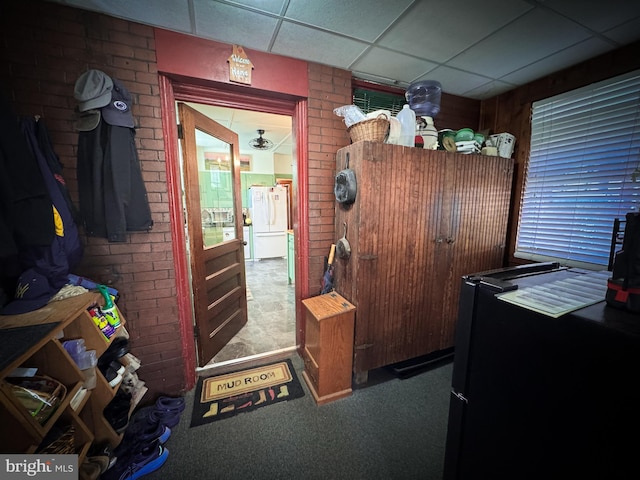 interior space featuring a paneled ceiling, carpet, and brick wall