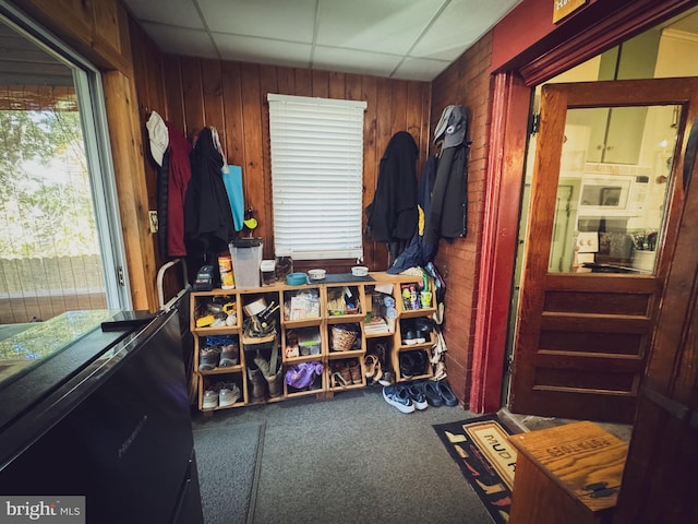 misc room with wooden walls, a drop ceiling, and carpet floors